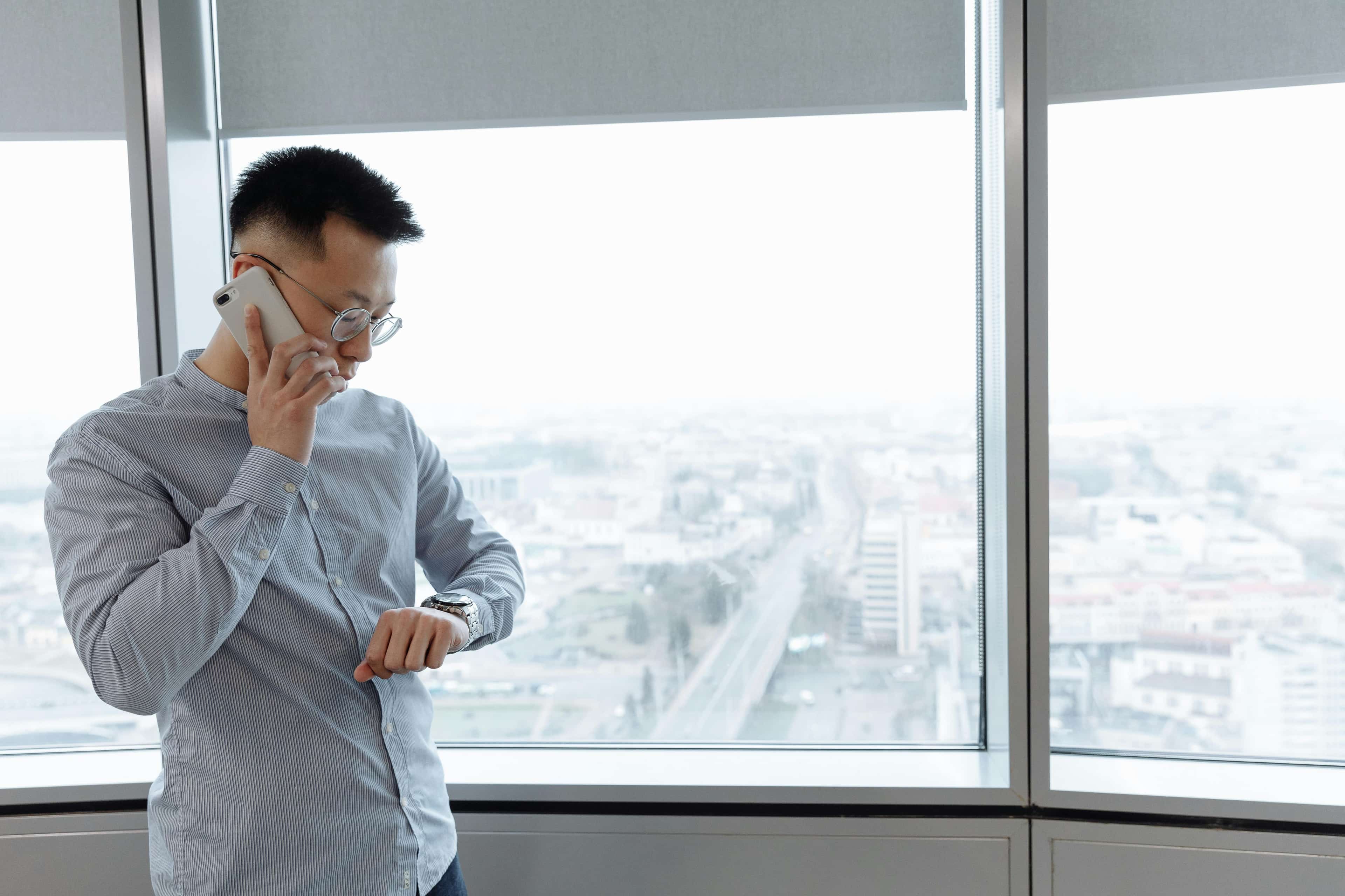 Responder on a phone call checking a watch, representing time-sensitive hotline coverage.