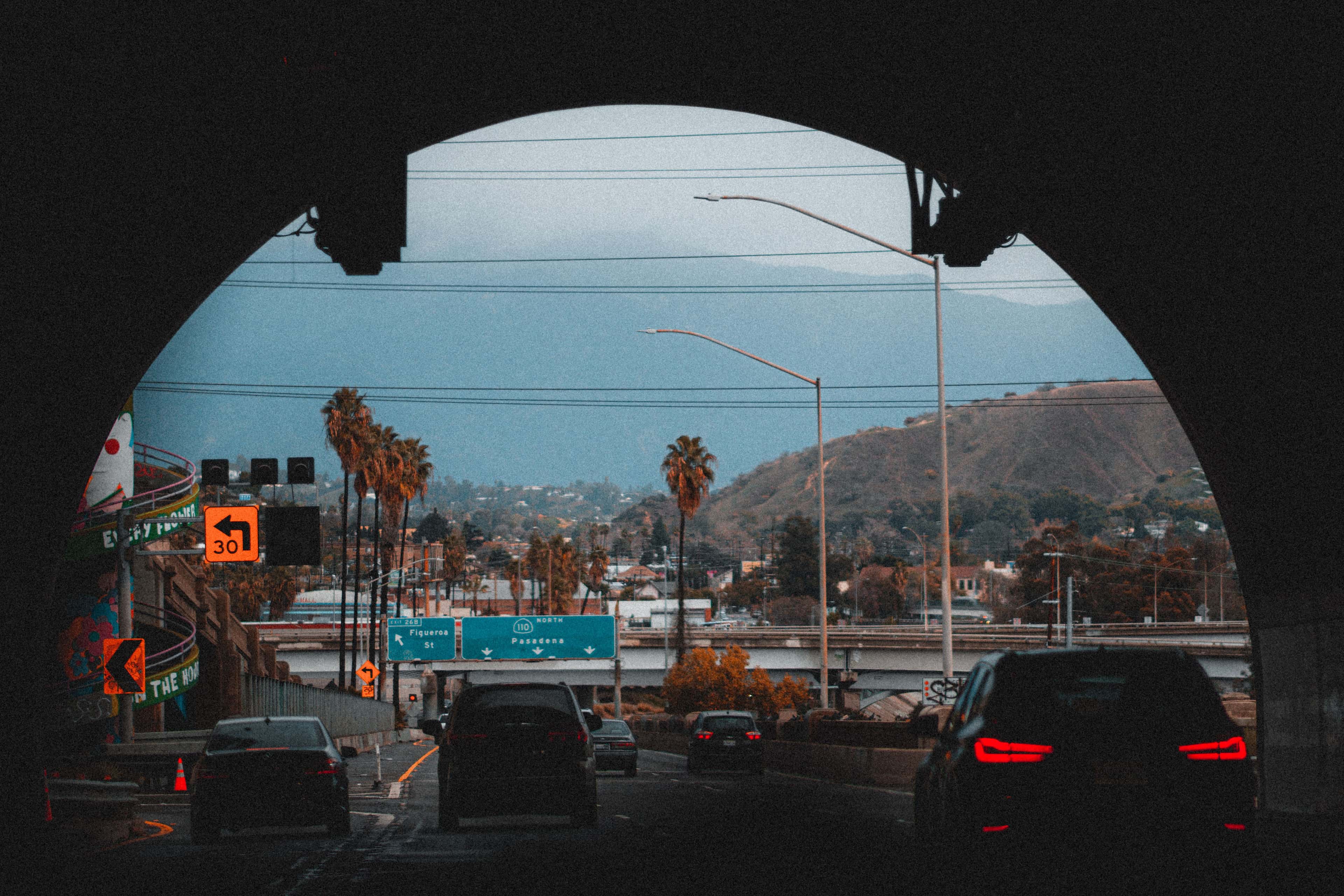 Highway tunnel view with palm trees and mountains in Los Angeles