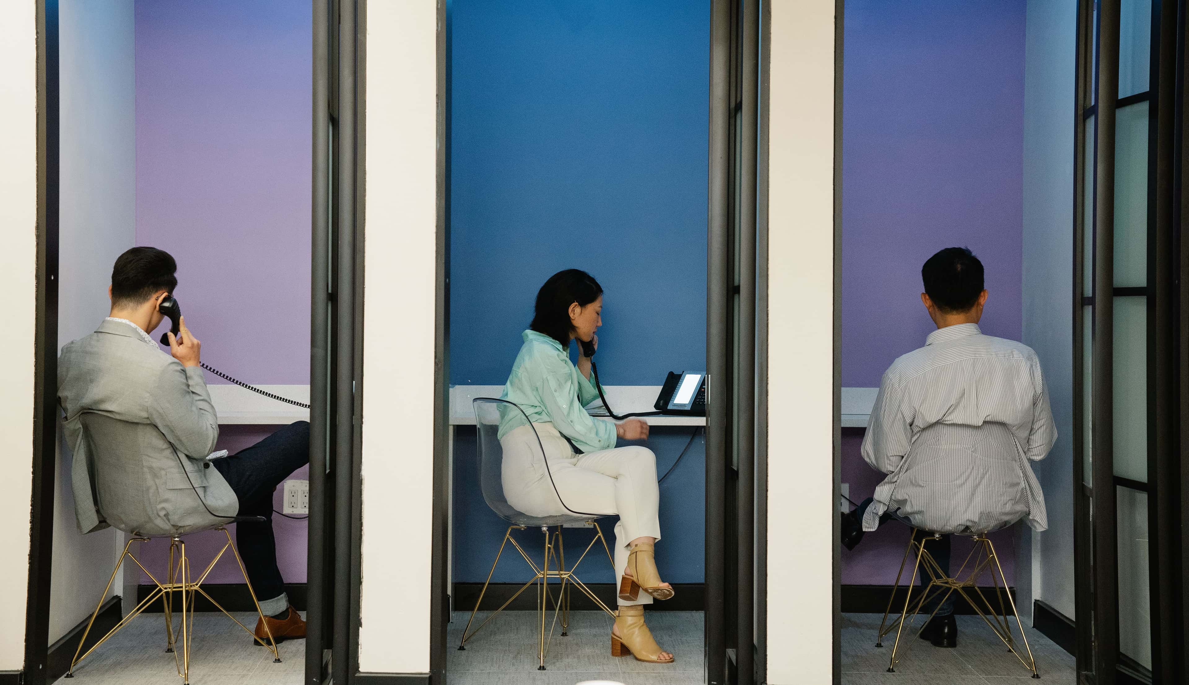 Business professionals using phone booths for communication in a modern office space