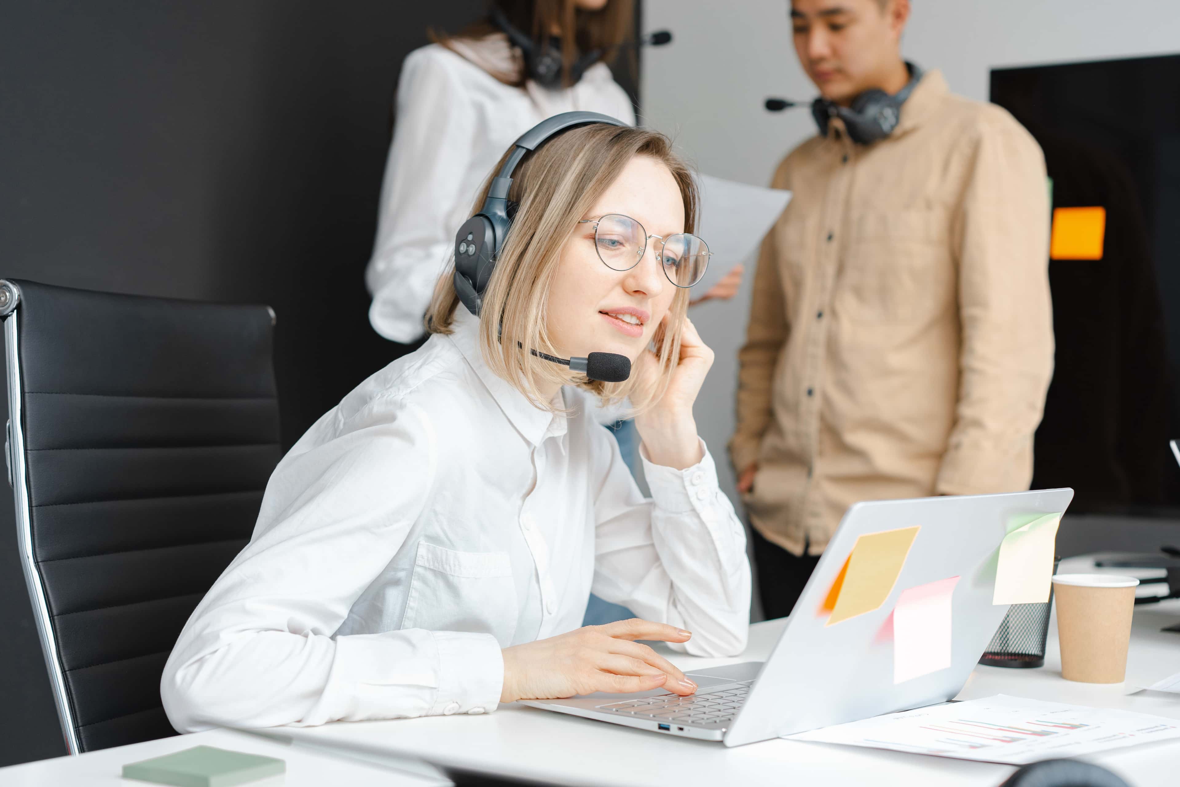 Customer support professionals working with headsets and laptops in a modern office environment
