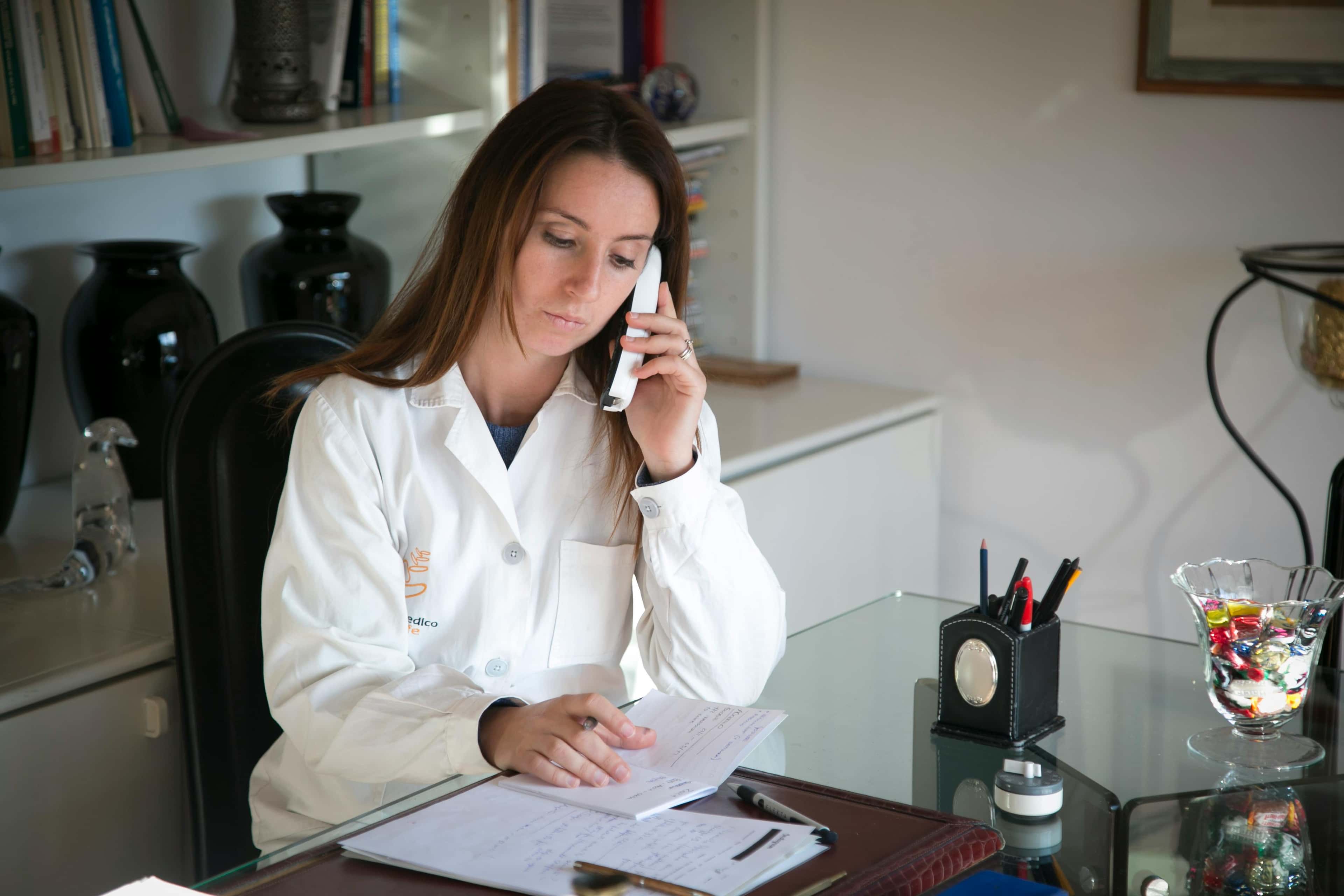 Clinician on the phone reviewing notes, representing after-hours site escalation.