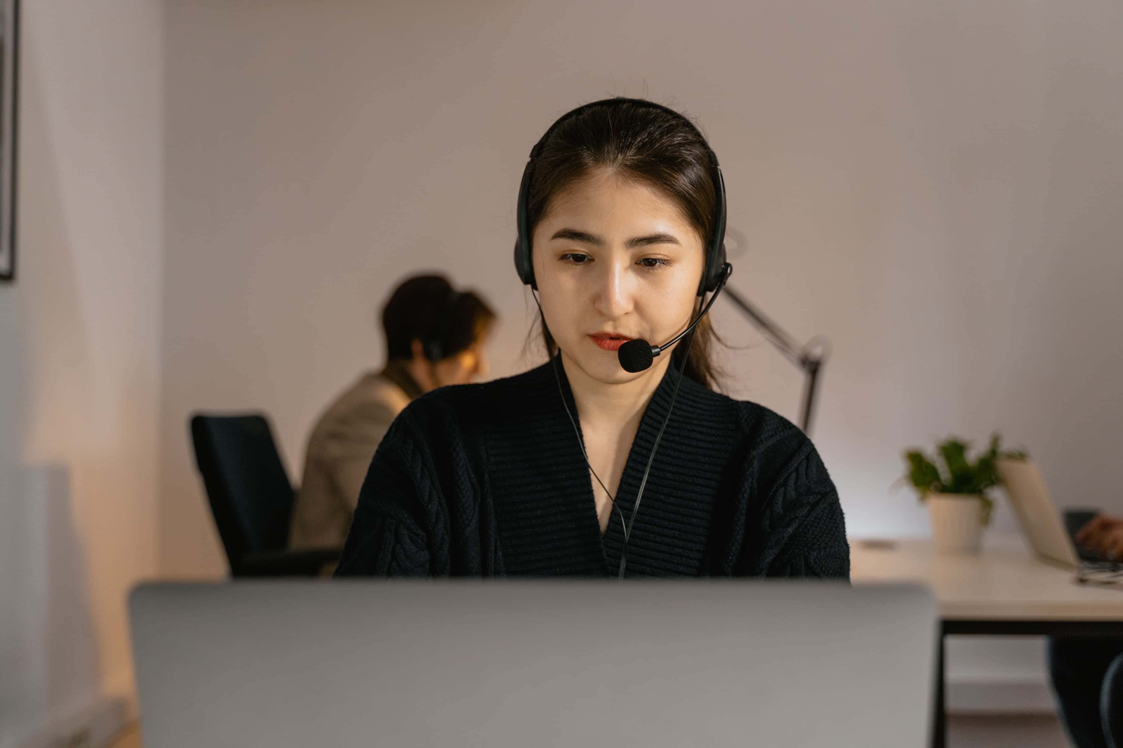 Professional call center agent in headphones diligently working on a computer indoors