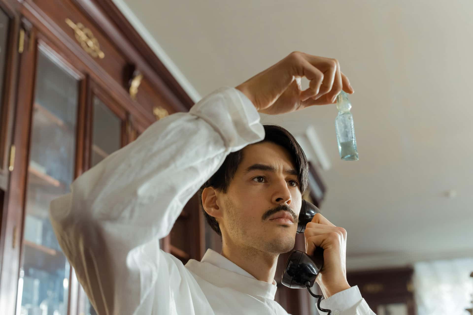 Scientist on the phone holding a small bottle in a lab setting