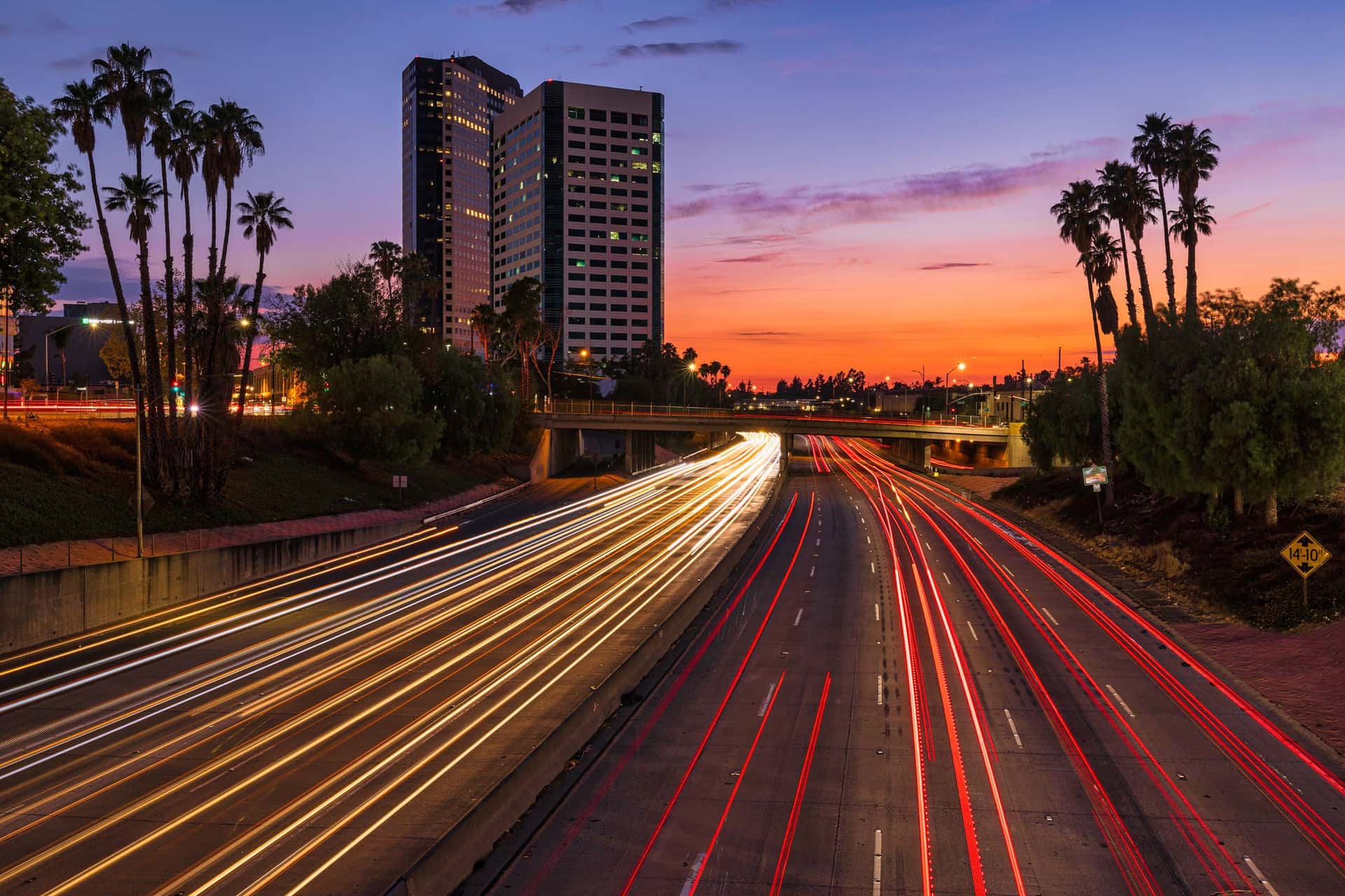 Sunset view of a Burbank highway with palm trees and light trails